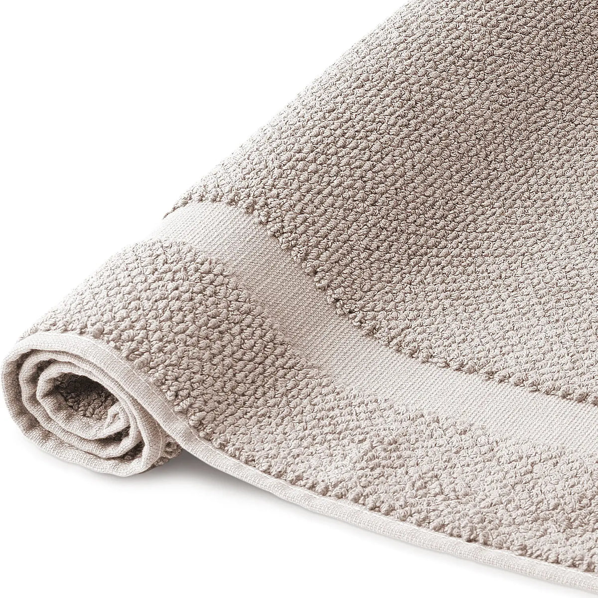 Spa Badvorleger Sandgrau 2er Set – Nahaufnahme der Seite, aufgerollter Badvorleger mit grob strukturiertem Bouclé-Frottier und hellem Rahmenabschluss, warmer Sandgrauton, 100% Baumwolle