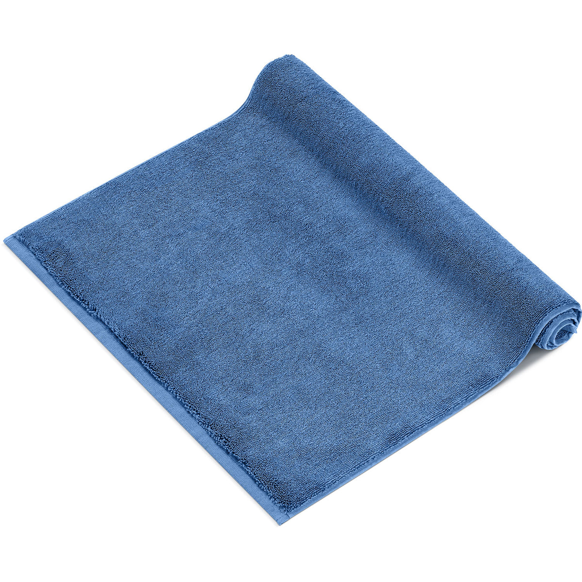 Pura Badvorleger Blau – einzelner Badvorleger von schräg oben, halb aufgerollt auf weißem Hintergrund, flauschiges blaues Frottier mit umlaufender Veloursbordüre, 100% Baumwolle 1200 g/m²