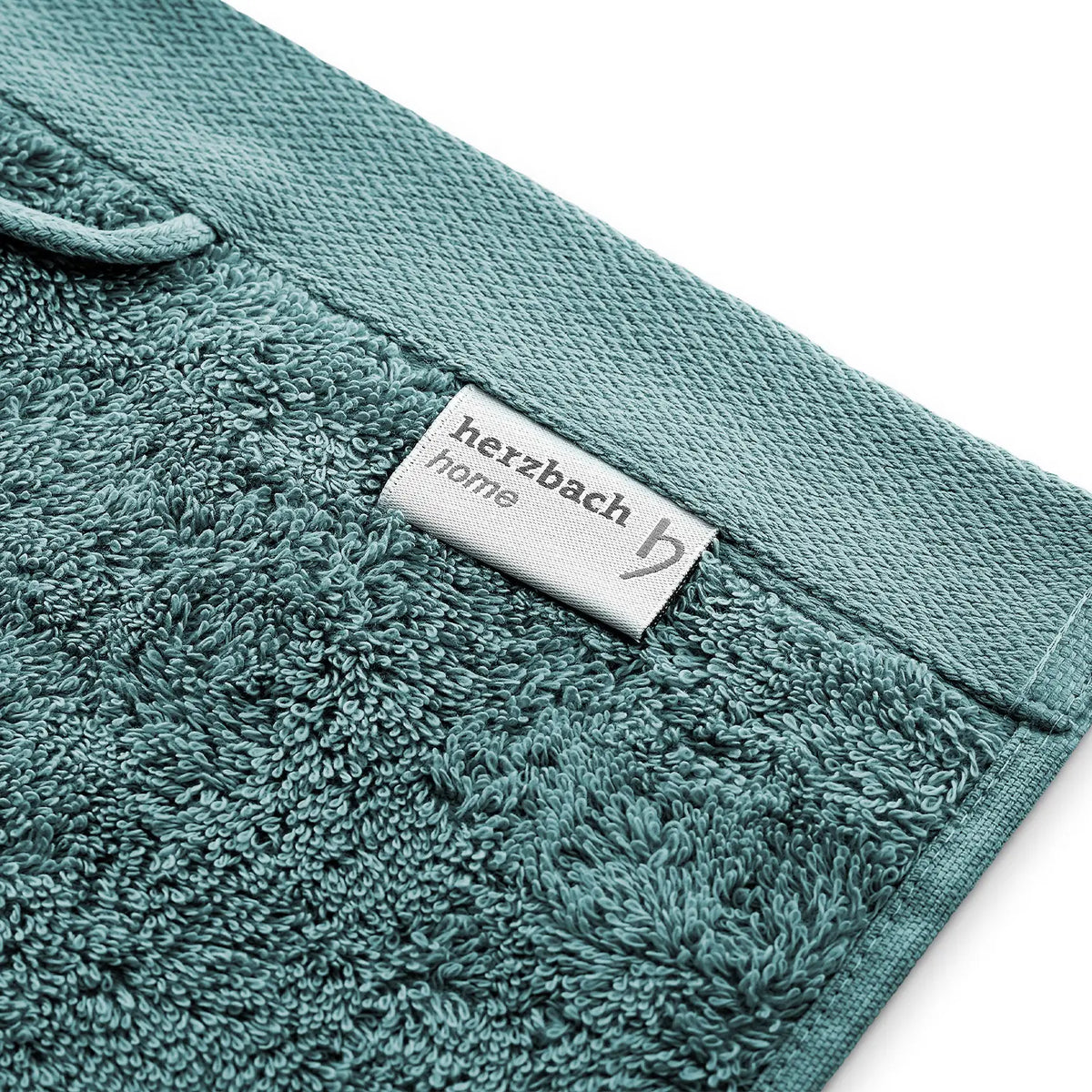 Pura Seiftuch Ozeangrün – Eckendetail mit herzbach home Stoffetikett, Aufhängeschlaufe und Velourssaum in Schrägansicht