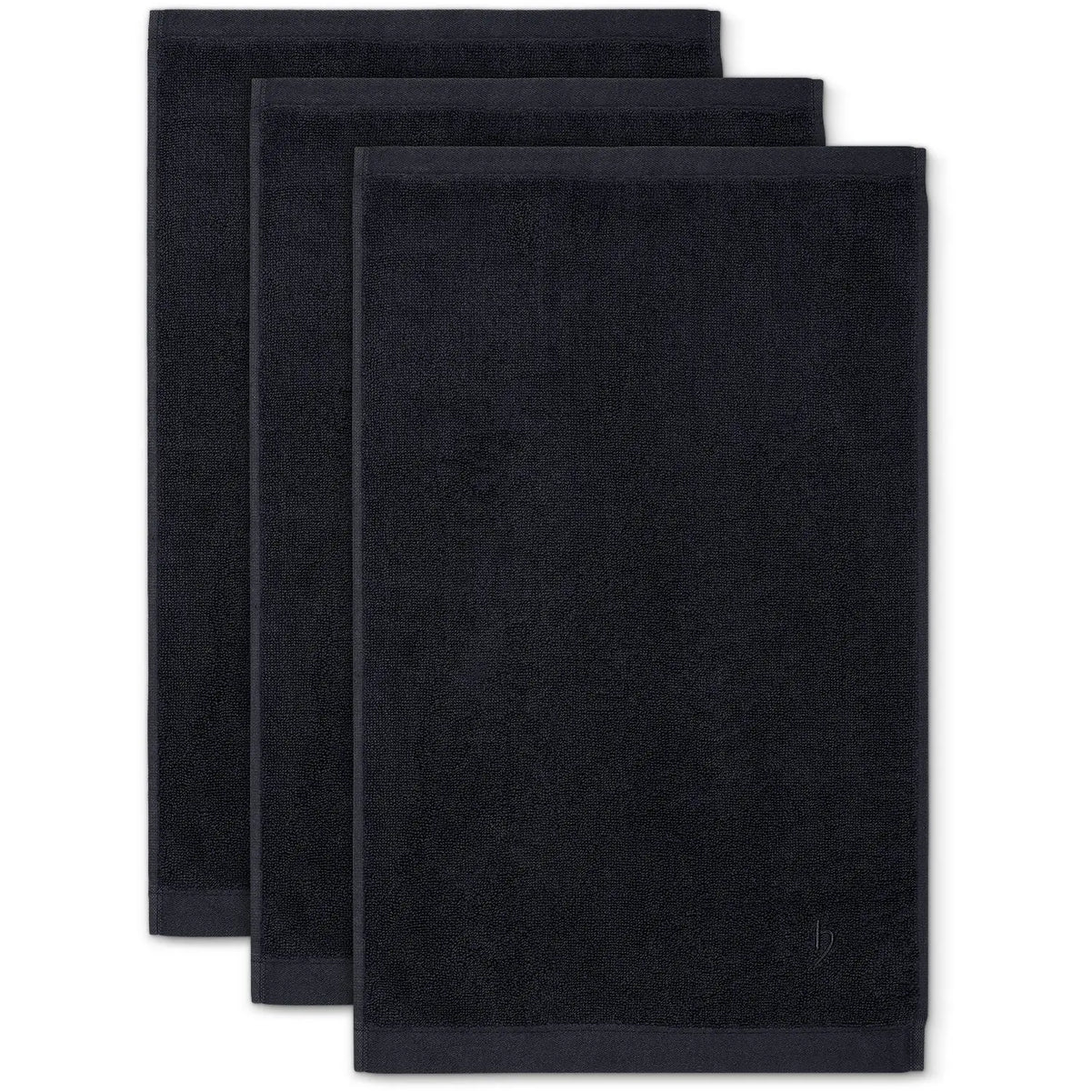 Gästehandtuch Deep Black 3er Set – drei flach ausgebreitete Gästehandtücher in Draufsicht nebeneinander versetzt, tiefschwarzes Frottier mit satiniertem Saum und feiner herzbach home Logoprägung, 30 x 50 cm