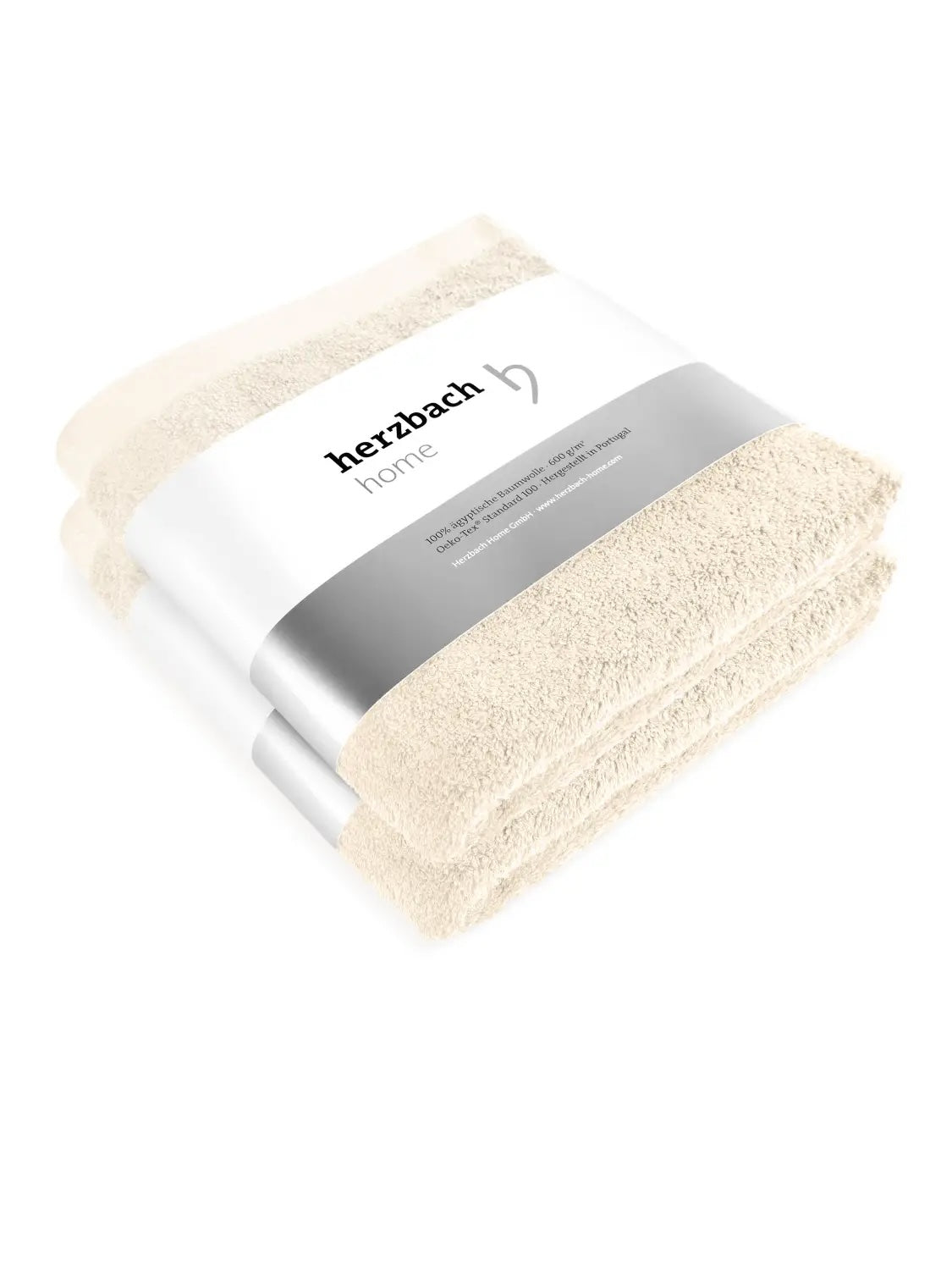 Zwei gefaltete cremefarbene Pura Handtücher mit herzbach home Papierbanderole