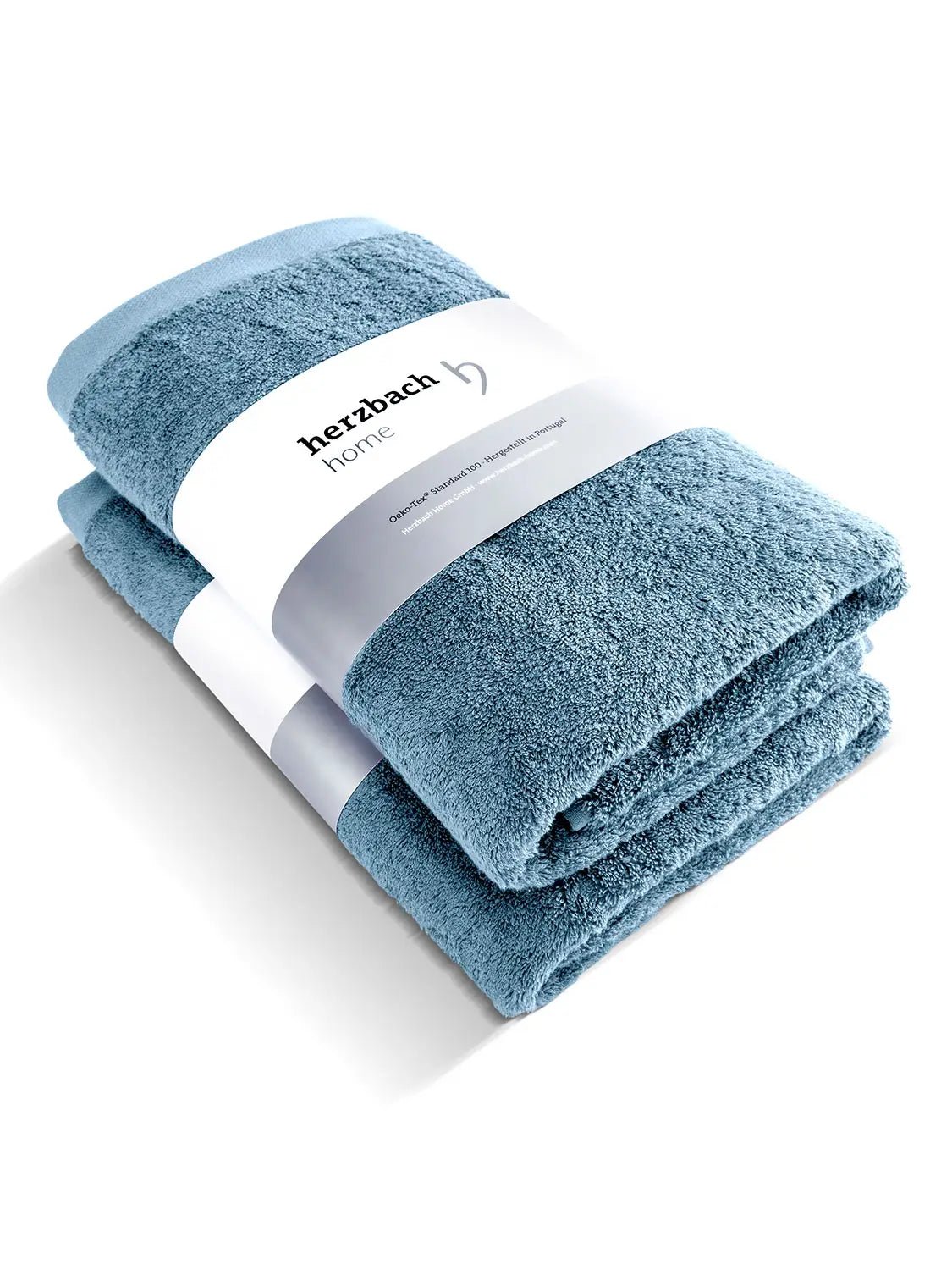 Zwei gefaltete blaue Pura Duschtücher mit herzbach home Papierbanderole