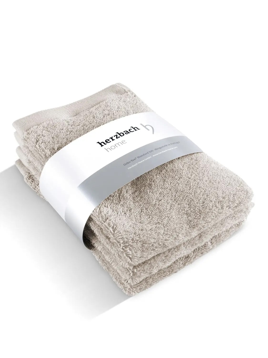 Drei gefaltete silbergraue Pura Gästehandtücher mit Herzbach Home Papierbanderole