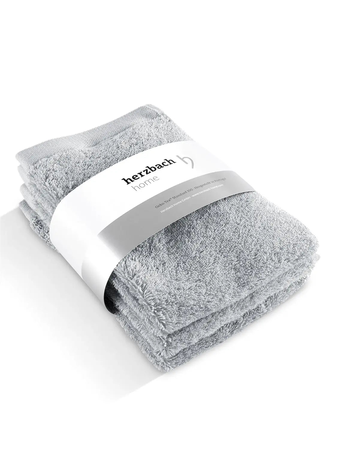 Drei gefaltete silbergraue Pura Gästehandtücher mit Herzbach Home Papierbanderole