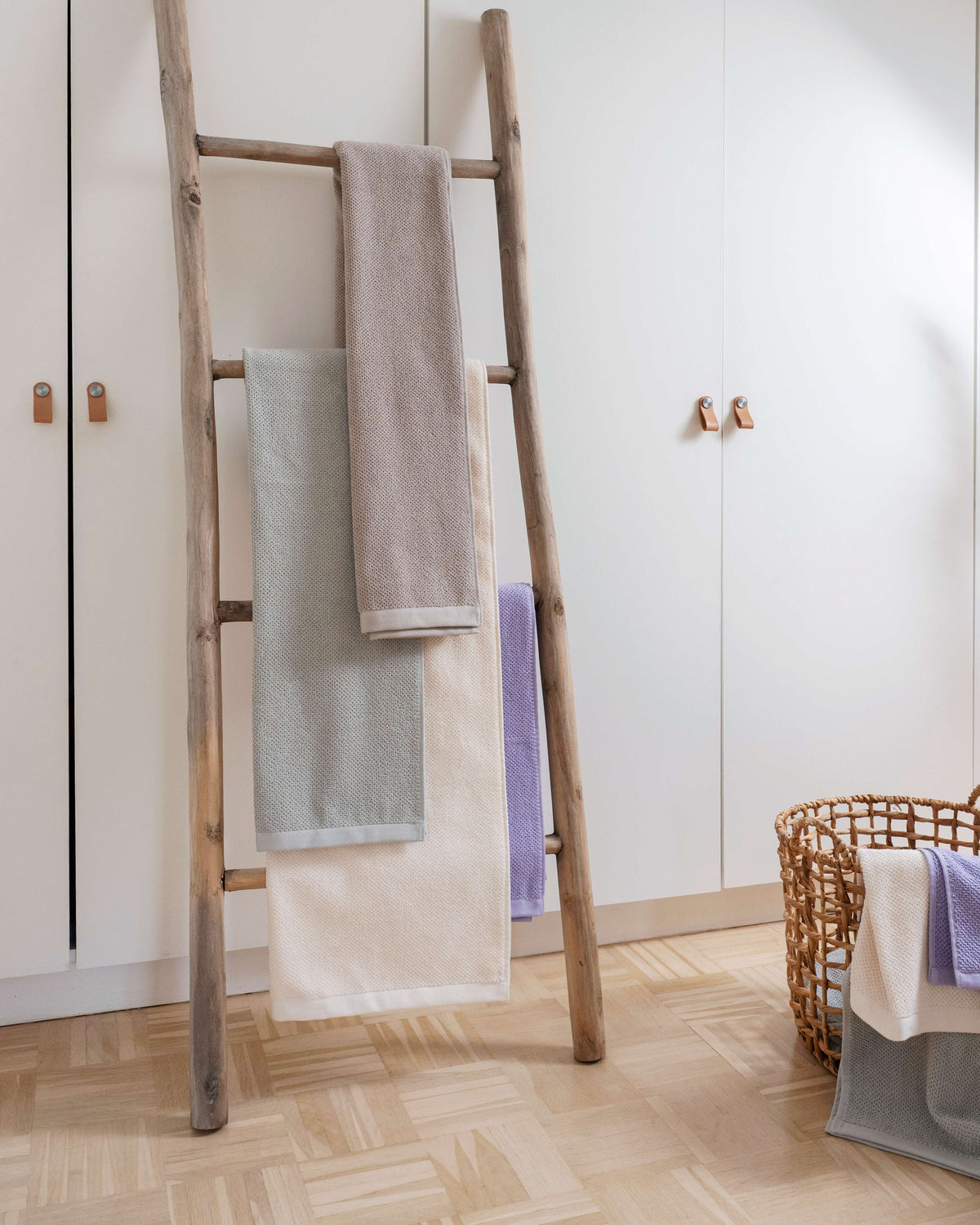 SPA Handtücher in verschiedenen Farben auf einer rustikalen Holzleiter – Sandgrau, Hellgrau, Weiß und Lavendel im Badezimmer-Styling