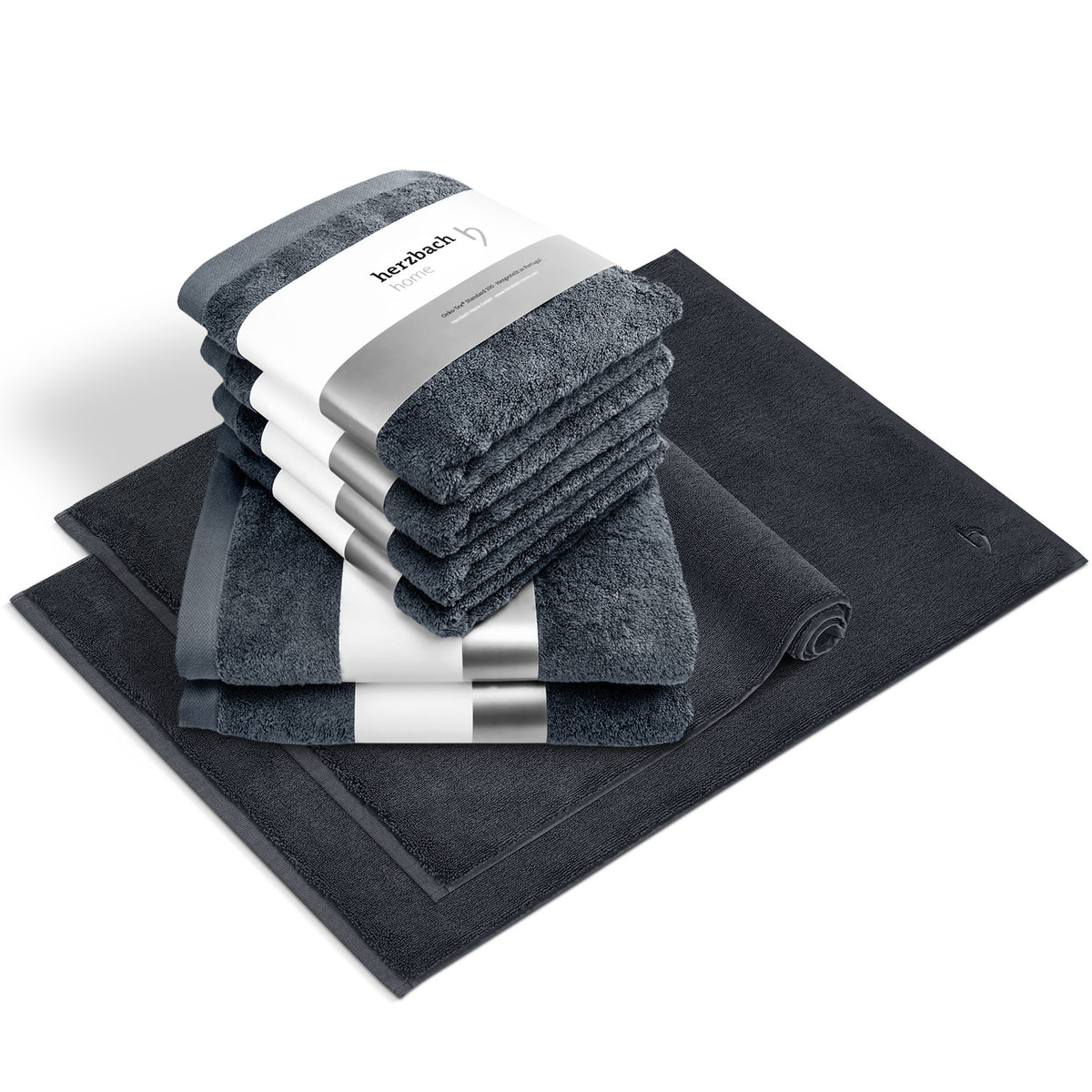 Pura Bundle Anthrazit – 6 gefaltete Handtücher mit herzbach home Banderole, ein aufgerollter und ein flacher Badvorleger im Set, weißer Hintergrund