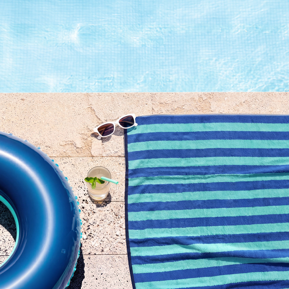 Duschtuch Good Vibes Türkis Blau am Poolrand ausgebreitet – Sommerfeeling von oben mit Schwimmring, Sonnenbrille und Erfrischungsgetränk