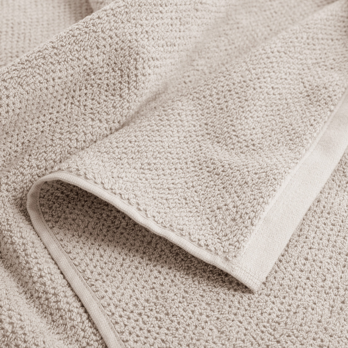 Detailansicht SPA Handtuch Sandgrau – grobe Waffelstruktur und glatter Satin-Abschluss im Nahvergleich