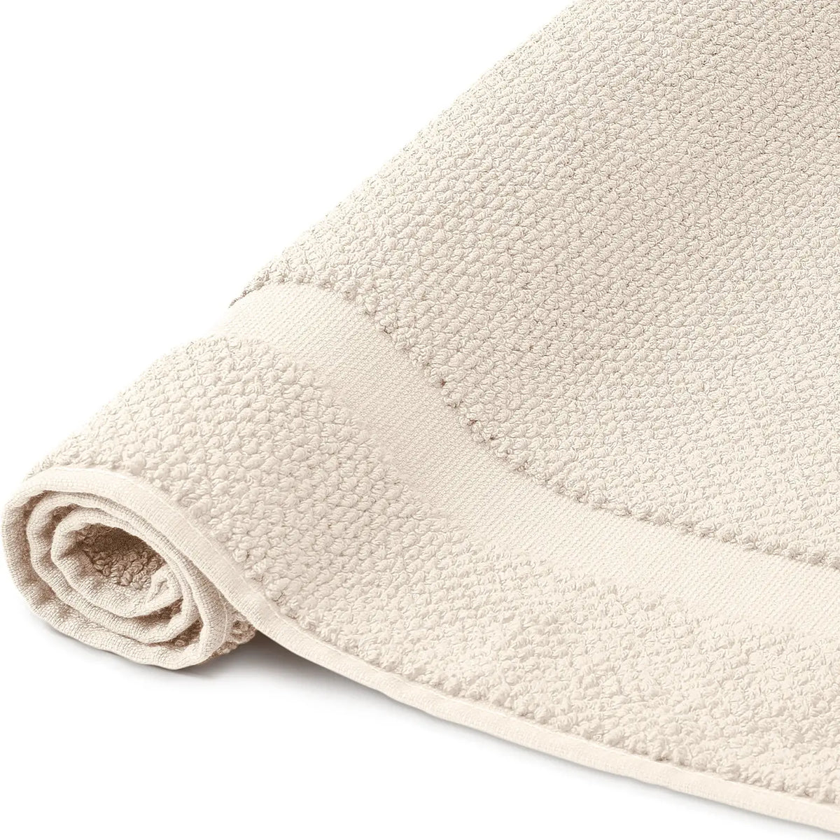 Spa Badvorleger Creme 2er Set – Nahaufnahme der Seite, aufgerollter Badvorleger mit grob strukturiertem Bouclé-Frottier und hellem Rahmenabschluss, warmer Cremeton, 100% Baumwolle
