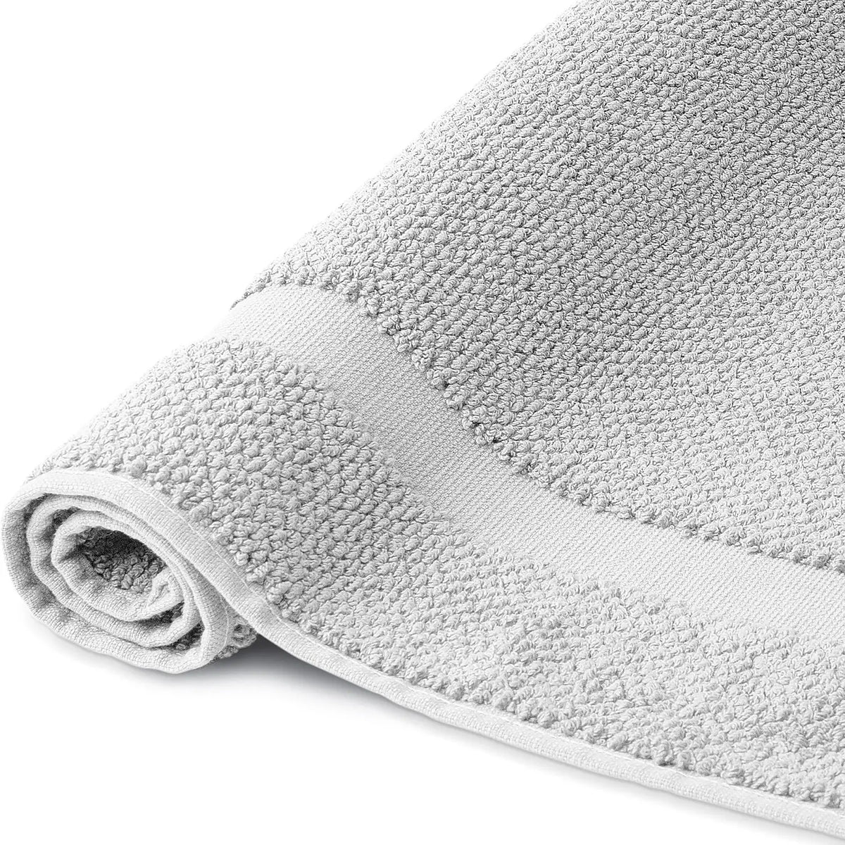 Spa Badvorleger Silbergrau 2er Set – Nahaufnahme der Seite, aufgerollter Badvorleger mit grob strukturiertem Bouclé-Frottier und hellem Rahmenabschluss, kühler Silbergrauton, 100% Baumwolle
